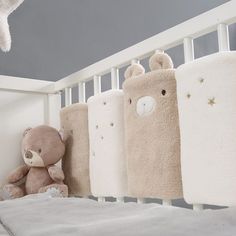 a teddy bear is sitting next to four baby cribs that are lined up