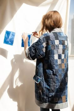 a woman is painting on the wall with blue squares