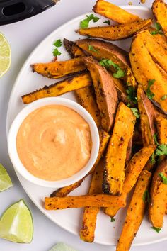 a white plate topped with sweet potato wedges next to a bowl of dipping sauce