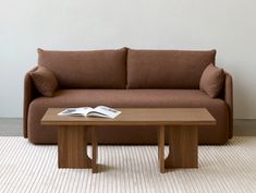 a brown couch sitting next to a wooden coffee table on top of a white rug