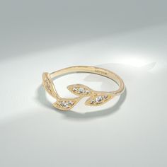 a gold ring with white stones on it sitting on a table next to a shadow