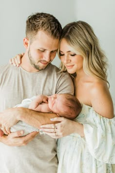 a man and woman holding a baby in their arms