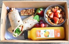 an open lunch box with fruit, salad and burritos