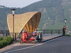 a scooter is parked in front of an outdoor kiosk with a person standing next to it