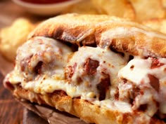 a meatball sub sandwich with cheese and sauce on it next to some french fries