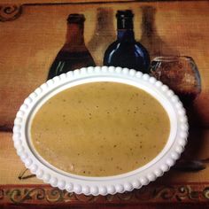 a white bowl filled with soup next to two wine bottles