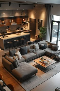 a living room filled with furniture next to a kitchen and dining area on top of a hard wood floor