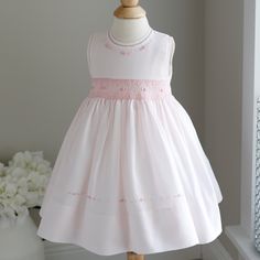 This Sweet Little Smocked Dress Is By Feltman Brothers Fine Children's Apparel. The Pale Pink Hue Looks Like Cotton Candy! The Sleeveless Style Will Keep Your Baby Girl Cool During Summer Months. The Detail In This Dress Is Super Appealing. The Rounded Neckline And The Arm Openings Have A Matching Pink Trim That Has Been Hand Faggoted (A Very High-End Stitching Detail) The Bodice Meets The Waist With A Petite Piping And Follows With Gorgeous Smocking Done In A Contrasting Pink Shade Of Embroider Pink Smocked Bodice Dress For Dress-up, Pink Dress With Smocked Bodice For Dress-up, Cute Fitted Sleeveless Smocked Dress, Spring Sleeveless Smocked Dress For Playtime, Sleeveless Smocked Dress For Spring Playtime, Sleeveless Smocked Dress For Summer Playtime, Fitted Sleeveless Smock Dress, Sleeveless Ruffled Smocked Dress For Playtime, Sleeveless Smocked Dress With Ruffles For Playtime