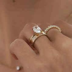 a woman's hand with two gold rings on top of her finger and one diamond ring in the middle