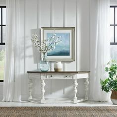 a white table with vases and flowers on it in front of a large window