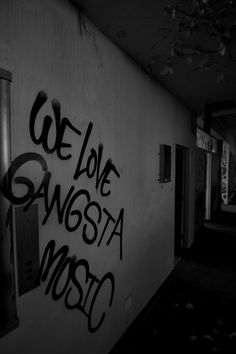 black and white photograph of graffiti on the side of a building in an alleyway