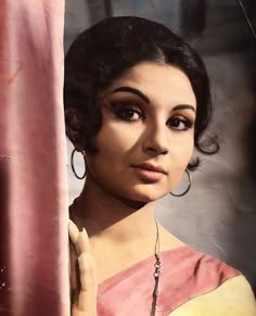 an old photo of a woman with large hoop earrings on her head, looking out from behind a curtain