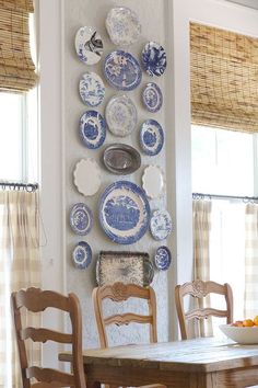 a dining room table and chairs with plates on the wall