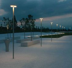 a row of benches sitting next to each other on top of a cement field at night