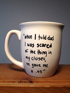 a white coffee cup with writing on the inside and outside, sitting on top of a wooden table