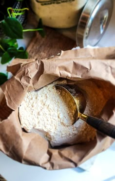 a wooden spoon in a bowl filled with white powder and brown paper on top of a table