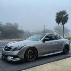 a silver sports car parked in a parking lot on a foggy, overcast day