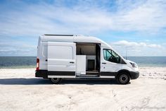 a white van parked on top of a sandy beach