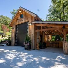 a garage with a covered patio and outdoor dining area in the back yard, surrounded by greenery