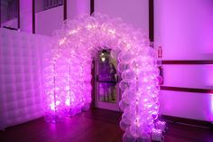 an arch made out of balloons with purple lights on the top and bottom, in front of a doorway