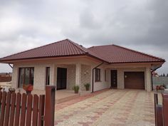 a house with a fence in front of it that has a brown door and two windows