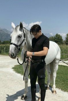 a man standing next to a white horse