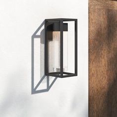 an outdoor light mounted on the side of a wall next to a wooden door and window