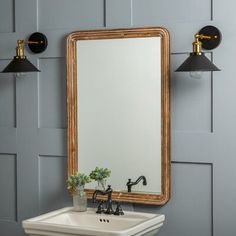 a bathroom sink sitting under a mirror next to a wall mounted faucet with two lights on it