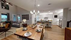 a large open concept living and dining room with wood flooring, white walls, gray couches, and wooden table