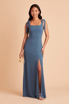 a woman wearing a blue dress with one side slit