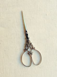 a pair of scissors sitting on top of a white cloth covered table next to each other