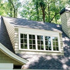 a house that has some windows on the side of it and trees in the background