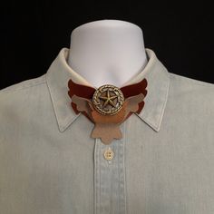 Wing Loops Neck Ties combine features of both a bow tie and a bolo tie. Its unique design is recognized by US Patent: 9,554664.  Made of Italian leathers and highlighted with a metal concho it offers a western appeal that fits with jeans and boots or combine with a tuxedo for a formal affair.  Dimensions: 3 1/2 inches wide x 3 inches tall x 1 inch thick Made with 2 layers of leather (Taupe and Whiskey) spiraled together and highlighted with a metal concho:  a center star with barbed wire border, Formal Brown Concho Jewelry, Western Style Concho Bolo Tie For Gift, Vintage Brown Jewelry For Western-themed Events, Western Style Brown Jewelry For Western-themed Events, Brown Concho Jewelry For Rodeo, Vintage Brown Jewelry For Rodeo, Western Brown Bolo Ties For Western-themed Events, Vintage Brown Bolo Tie With Concho, Brown Bolo Ties As A Gift