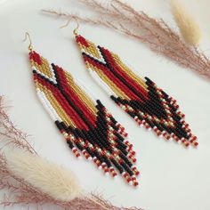 These long beaded earrings are inspired by the black, red and gold patters. Handcrafted with meticulous attention to detail, they exude timeless sophistication. Perfect for adding a touch of celestial charm to any ensemble, these earrings are sure to become a cherished addition to your jewelry collection. Dimensions: - Length: 12 cm (4.7 inches) - Width: 3 cm (1.2 inches) Bugle Bead Earrings, Red Bead Earrings, Long Beaded Earrings, Long Chandelier, Beaded Fringe Earrings, Brick Stitch Earrings, Earring Tutorial, Beaded Hoop Earrings, Beaded Hoops