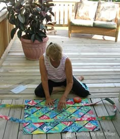 a woman is sitting on the ground making a quilt