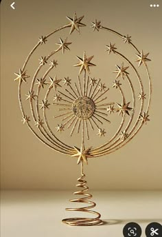 a gold christmas ornament with stars hanging from it's center and spirals in the middle