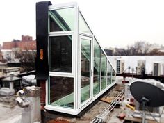 a glass house on top of a building with lots of construction equipment around it and buildings in the background