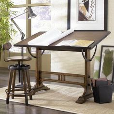 a desk with two stools in front of it and pictures on the wall behind it