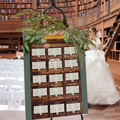 a bride and groom standing in front of a wooden table with seating cards on it