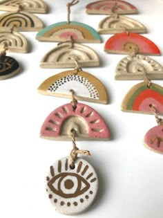 an assortment of handmade ceramic ornaments on a white surface with brown and pink accents