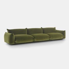 a green couch with four pillows on it's back and one arm facing the camera