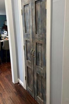 an open wooden door in a room with hard wood flooring and white paint on the walls