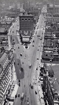 an old black and white photo of a city street with cars driving down the road