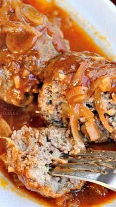 meatballs covered in gravy on a plate with a fork