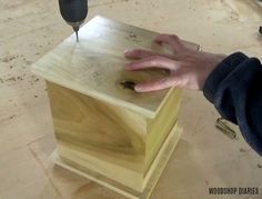 a person uses a drill to attach the top of a wooden box with holes in it