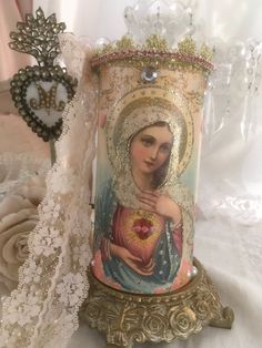 an ornate candle holder with the image of mary magdalene in gold and pink on it