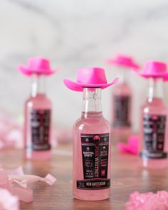 a pink bottle with a hat on top of it sitting on a table next to other bottles