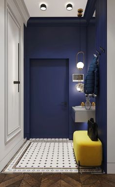 a hallway with blue walls and white tile flooring, yellow footstool in the foreground