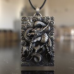 Dive into the rich tapestry of Eastern mythology with our Asian-Inspired Dragon 925 Sterling Silver Necklace. This piece embodies the spirit, power, and wisdom of the legendary Asian dragon, a symbol of prosperity, luck, and the balance of nature. Expertly crafted from premium 925 sterling silver, the necklace showcases a detailed pendant reflecting the intricate artistry of Asian dragon designs. Its unique design ensures it stands out, making it a conversation starter wherever you go. Whether y Spiritual Etched Rectangular Jewelry, Collectible Etched Amulet Jewelry, Silver Symbolic Rectangular Jewelry, Carved Silver Necklace For Gift, Silver Carved Necklace For Gift, Spiritual Engraved Rectangular Jewelry, Collectible Etched Rectangular Jewelry, Handmade Fantasy Silver Jewelry, Handmade Silver Fantasy Jewelry