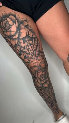 a woman's leg with tattoos and flowers on it, in black and white